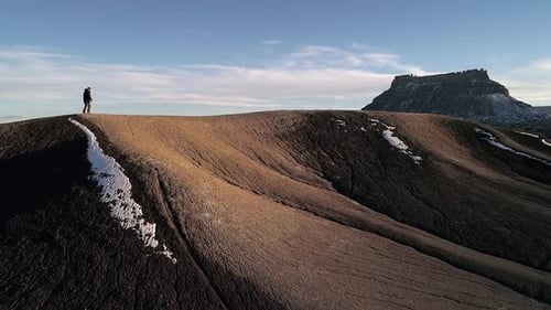 Lone hiker on ridge of sand dune walking in the desert