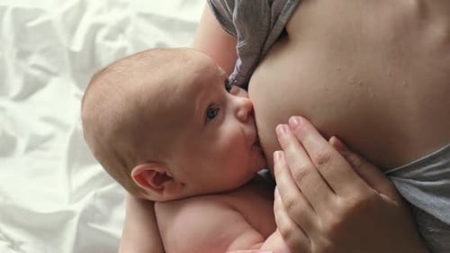 Mother Breastfeeding Newborn Infant at Home