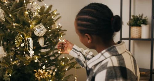 Girl Decorating Christmas Tree with Shiny Ornaments