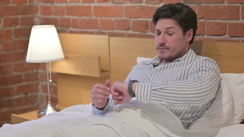 Middle Aged Man Checking Watch while Waiting in Bed
