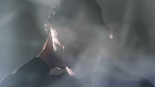 Man Massaging Neck in Smokey Background