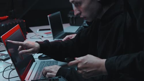 Hackers falando e usando o laptop no escuro do escritório