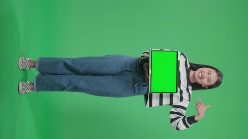 Asian Woman Holding And Pointing Green Screen Computer While Standing In Front Of Green Screen