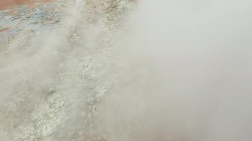 Adult Exploring Rocky Geothermal Area Through Steam