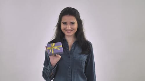 Smiling Woman Presents a Small Wrapped Gift