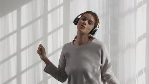 Woman Dancing with Headphones in Front of Window
