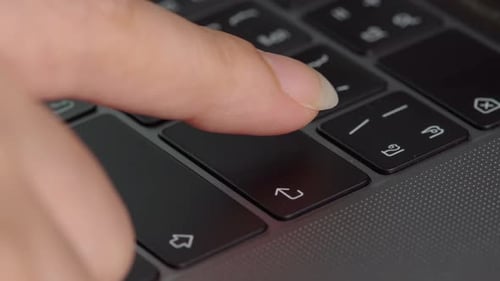 close-up female hand pressing enter button on a laptop keyboard