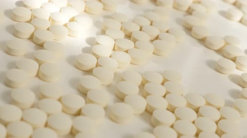 Scattered White Pills on a White Background