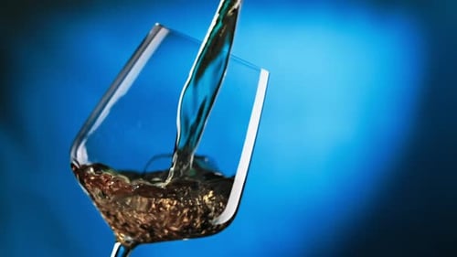 Wine Being Poured into Glass on Blue Background