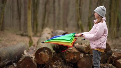 The Child Opens a Colorful Umbrella in the Rain