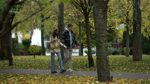 Wide Shot of Happy Young Couple Walking with Holding Hands Along Path