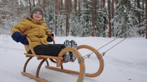 Happy Chubby Toddler sitzt im Holzschlitten und lächelt Happy Day im Forest Park im Winter