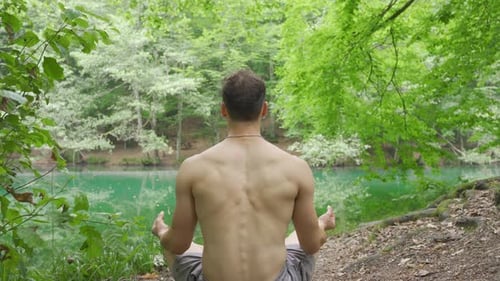 Man Meditating by Lake in Lotus Position