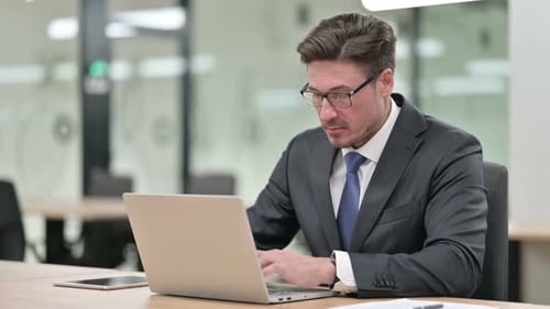 Focused Middle Aged Businessman Working on Laptop in Office