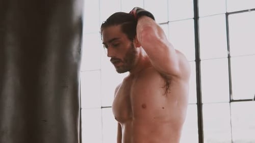 Sweaty Muscular Man with Boxing Gloves Next to Bag
