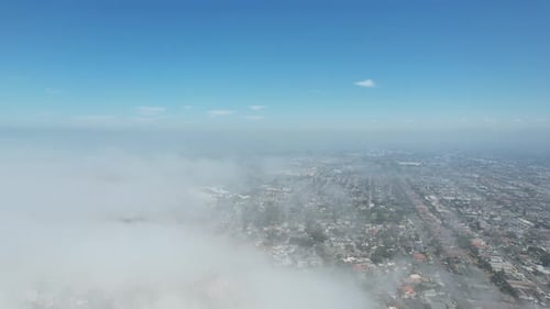 Aerial Cityscape Shrouded in Clouds Under Blue Skies