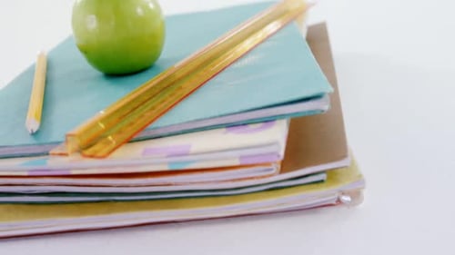 School Supplies Stacked With a Green Apple On Top