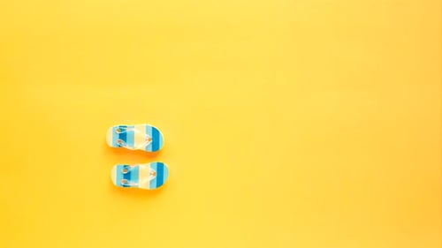 Blaue Flipflops gehen auf einem gelben Strand