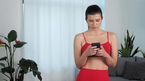 Woman Using Smartphone in Athletic Wear at Home