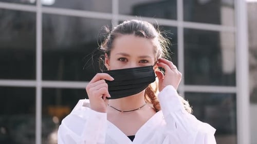 Woman Puts on Mask and Holds Up Hand