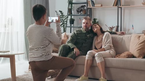 Boy Photographs Military Father With Wife at Home