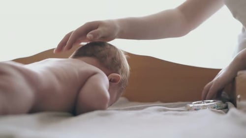 Gentle Hand Strokes Baby's Head on Changing Table