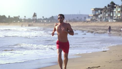 Male lifeguard running along the beach