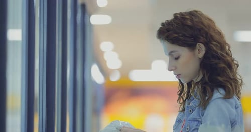 Niña elige alimentos congelados de la vitrina refrigerada en el supermercado