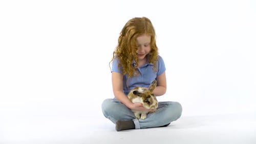 Young Girl Cradling Pet Rabbit in Studio