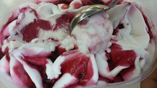 Spoon Scooping White Ice Cream with Berry Sauce