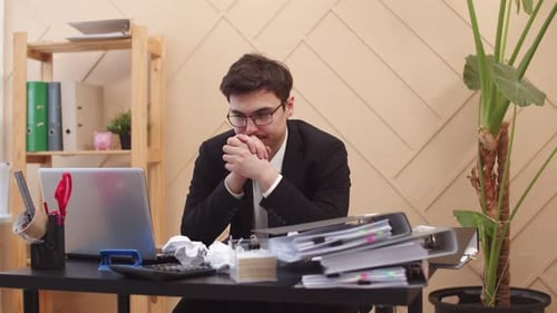 Man Stressed at Desk with Laptop and Paperwork