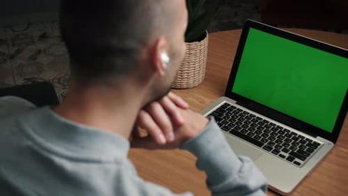 Closeup Back View Shot of Young Man Having a Video Call on the Laptop with Green Screen in the Home