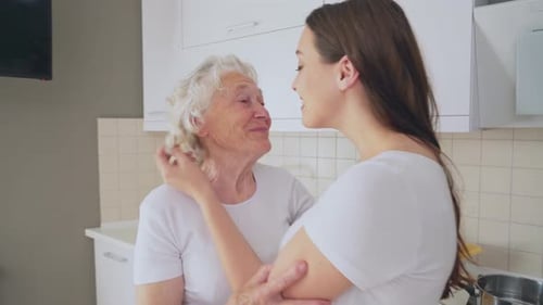 Grandmother and Granddaughter Embrace Affectionately in Kitchen