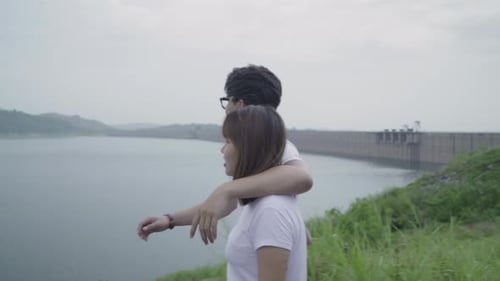 backpacker couple on hiking adventure feeling freedom walking in forest near lake in rainy day.