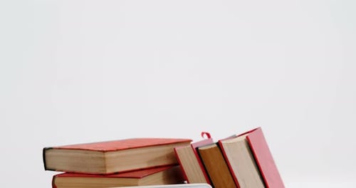 Stack of books with digital tablet against white background