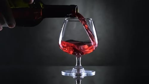 Pouring red wine into elegant glass