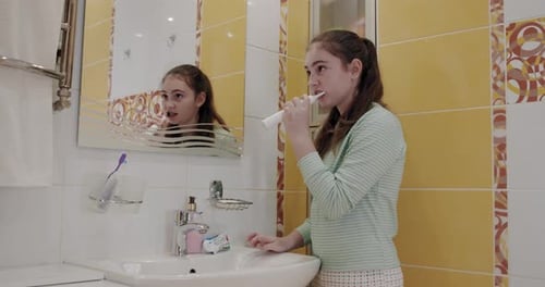 Girl Brushing Teeth in Bathroom at Home