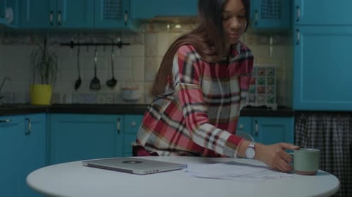 Woman Opens Laptop at Kitchen Table