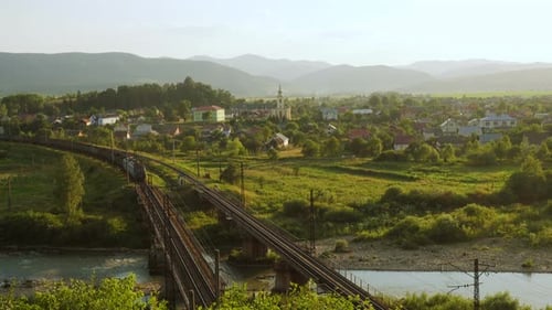 Trem passando pela ponte que atravessa a vila montanhosa