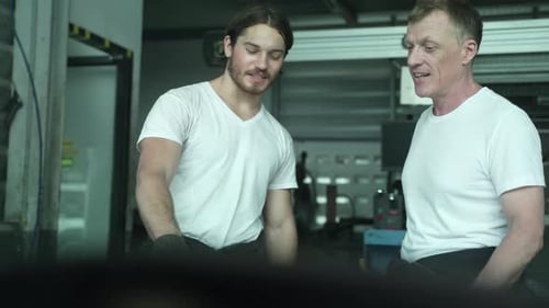 Two Auto mechanic working on car engine in mechanics garage. Repair service. Through mirror view.