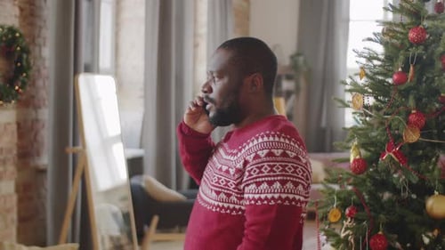 Man Talking on Phone Near Christmas Tree