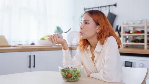 Asian young happy attractive woman eat green salad in kitchen at home for health care wellness.
