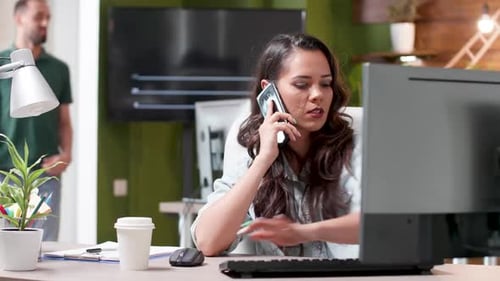 Woman Talking on Phone While Working on Computer