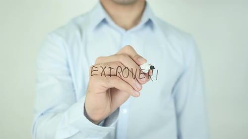 Man Writes the Word Extrovert on Clear Surface