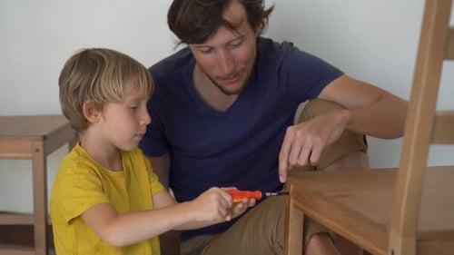 Father and His Little Son Are Assembling Furniture. They Assemble a Kitchen Chair