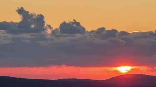 View of Sunset sun and clouds above the mountains.
