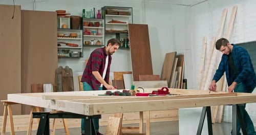 Jóvenes carpinteros construyen una pared de madera maciza en un taller de carpintería