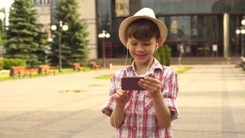 Boy with Hat Using Cell Phone Outside