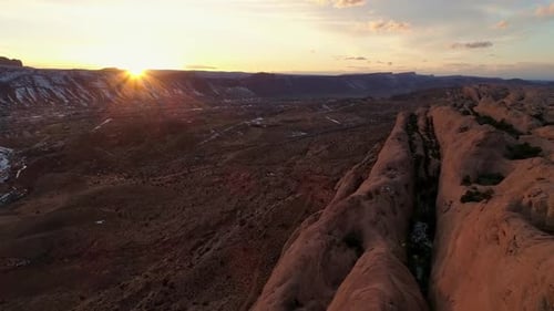 Über rote Felsklippen fliegen, während die Sonne in der Ferne untergeht