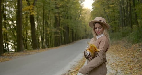 Blonde Woman Posing with Leaves in Autumn Park